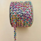 Spool of colorful braided rope on a beige background