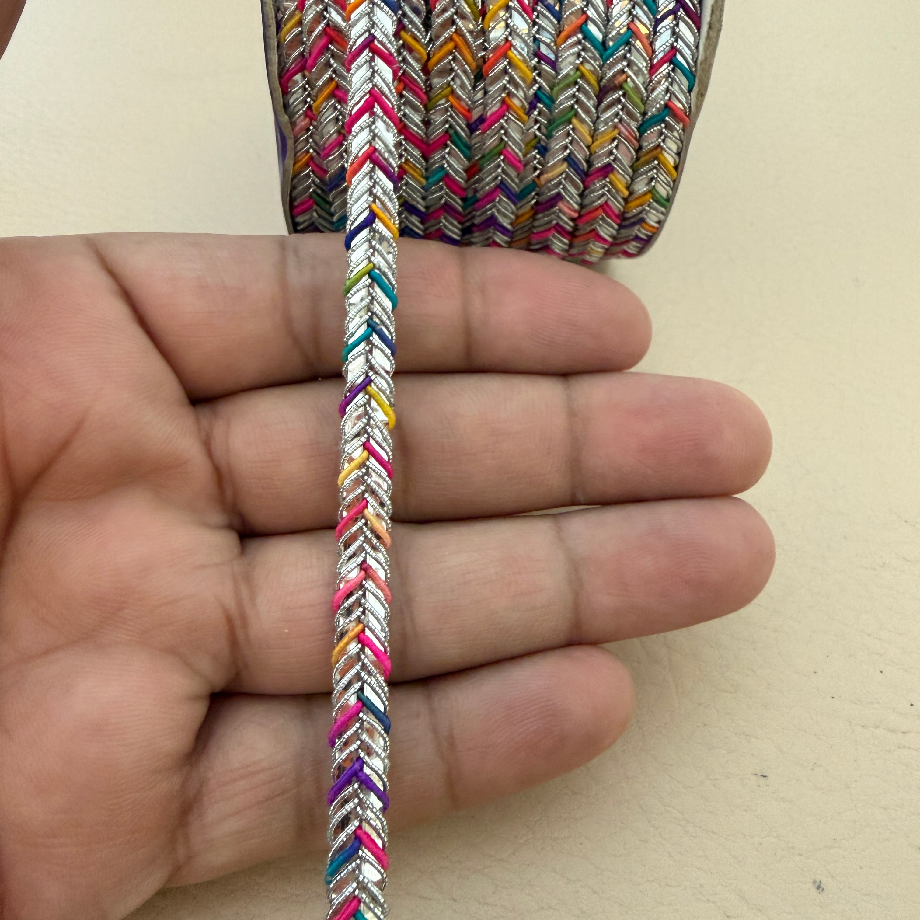 Multicolored braided cable held between fingers against a beige background