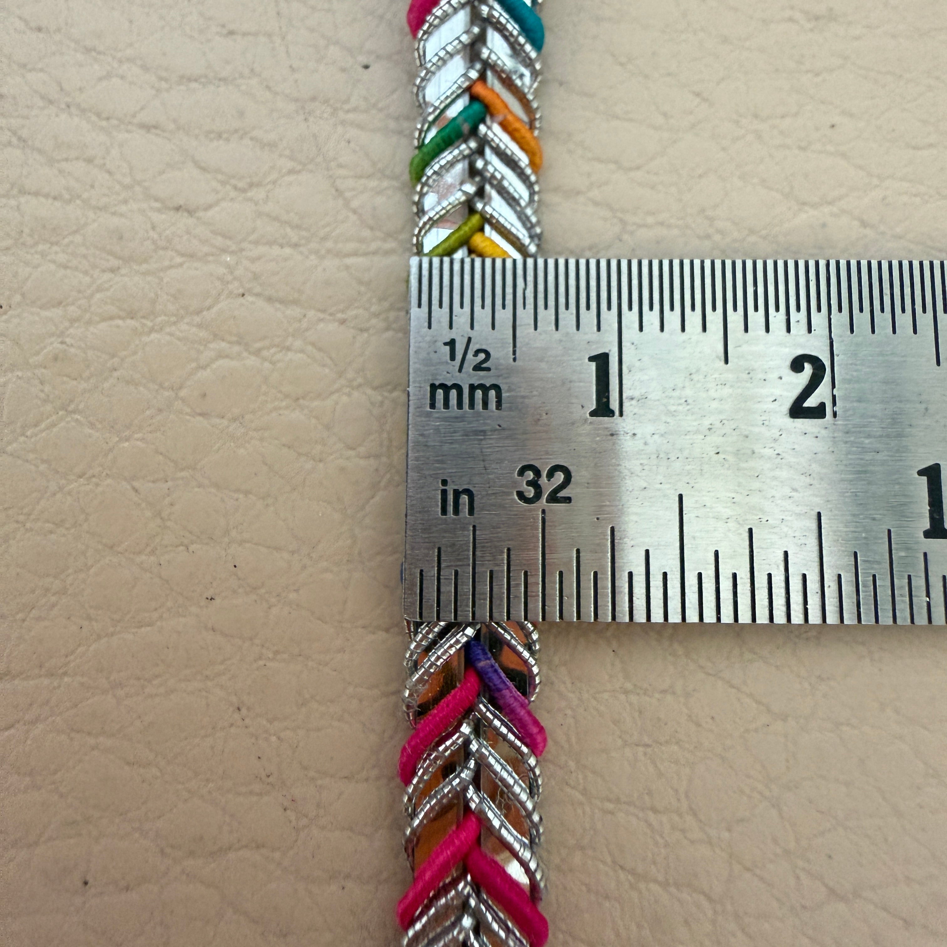 Colorful braided cord with a ruler for scale on a beige background