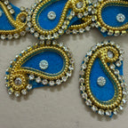 Decorative blue and gold paisley designs with crystals on a beige background
