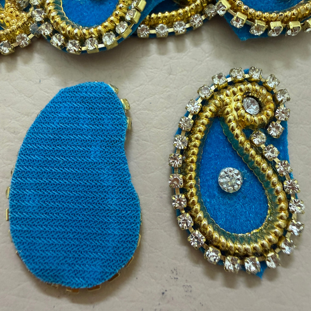 Decorative blue and gold earring components on a beige background