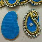 Decorative blue and gold earring components on a beige background