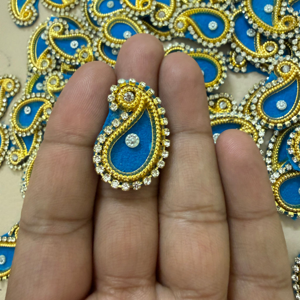 Decorative blue and gold ring on a hand with a patterned background