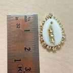 Gold and white decorative item next to a ruler on a beige background