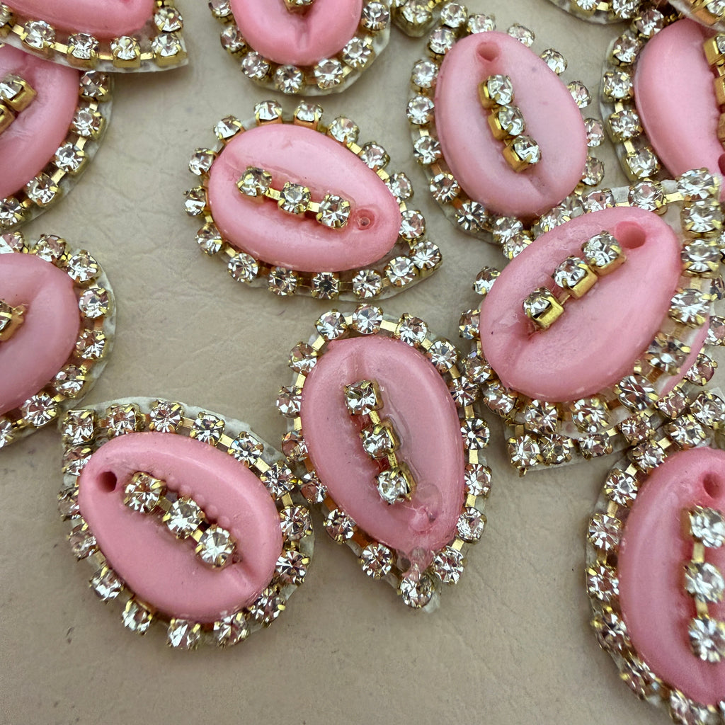 Pink rhinestone-encrusted buttons on a beige background