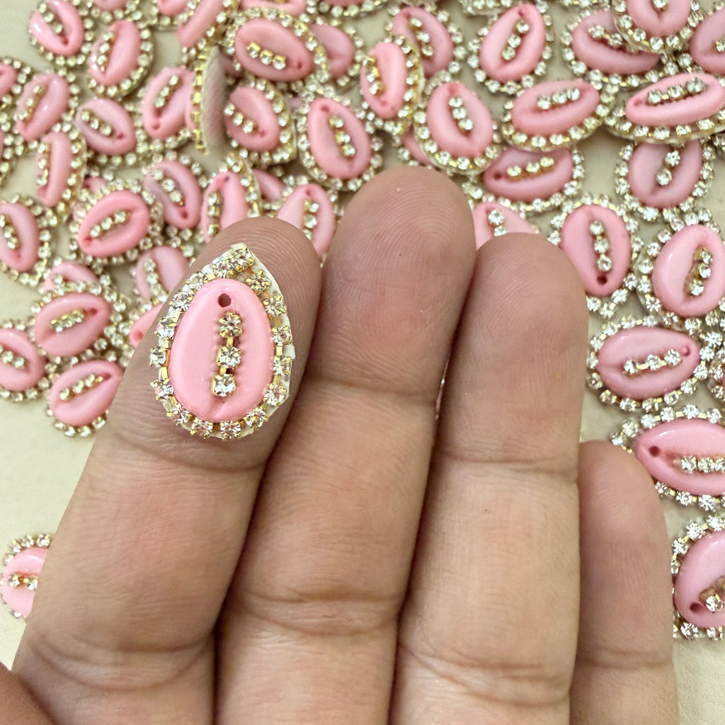 Close-up of a hand wearing a pink and gold ring with a decorative background.