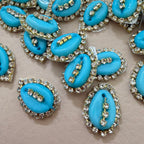 Blue teardrop-shaped embellishments with rhinestones on a beige background