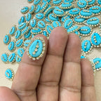 Turquoise decorative stones with gold accents on a hand