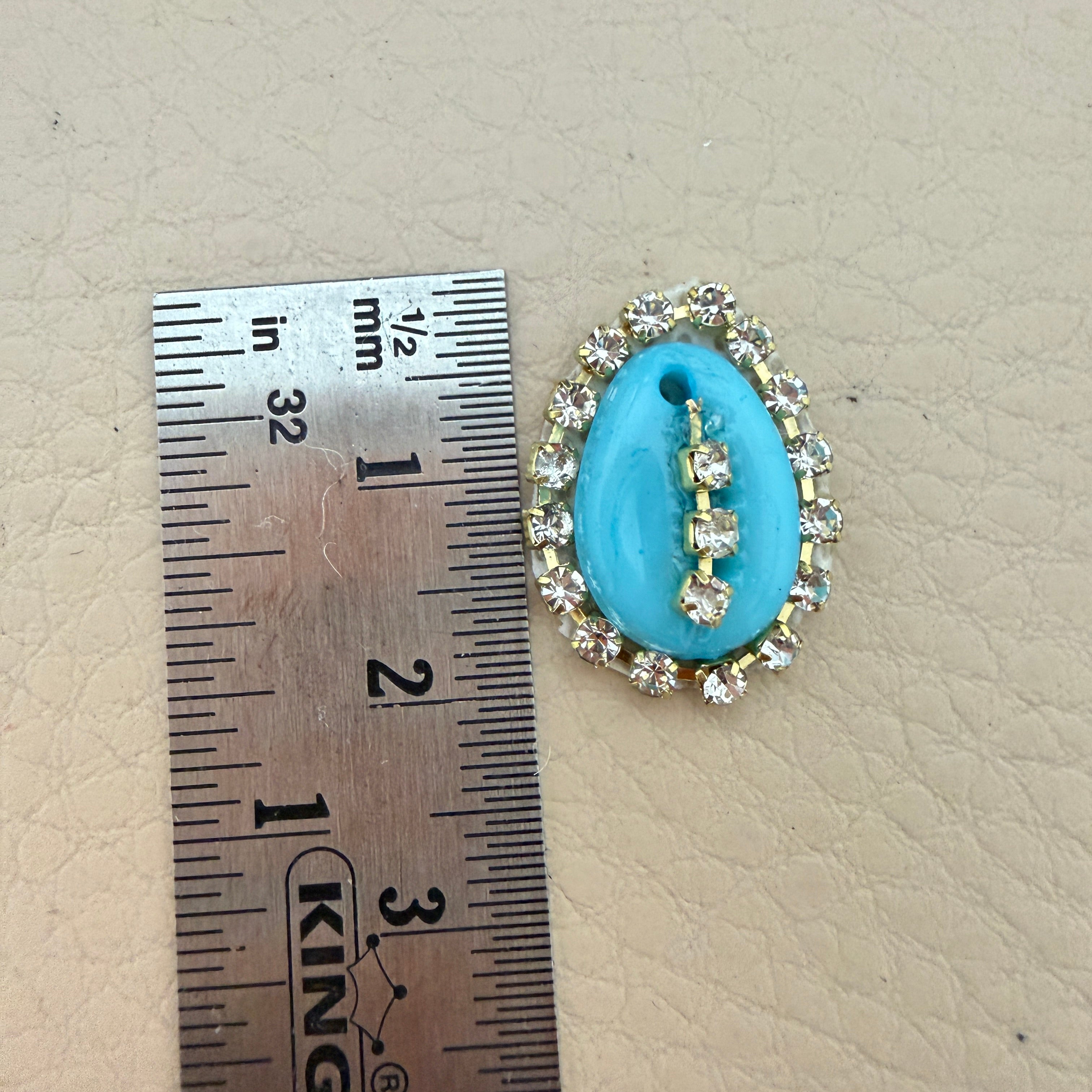 Turquoise stone with decorative border next to a ruler on a beige surface