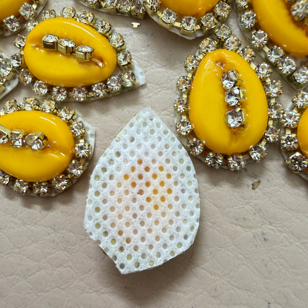 Yellow gemstones with rhinestone settings on a textured surface