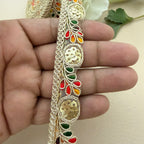 Decorative lace trim held between fingers with a neutral background