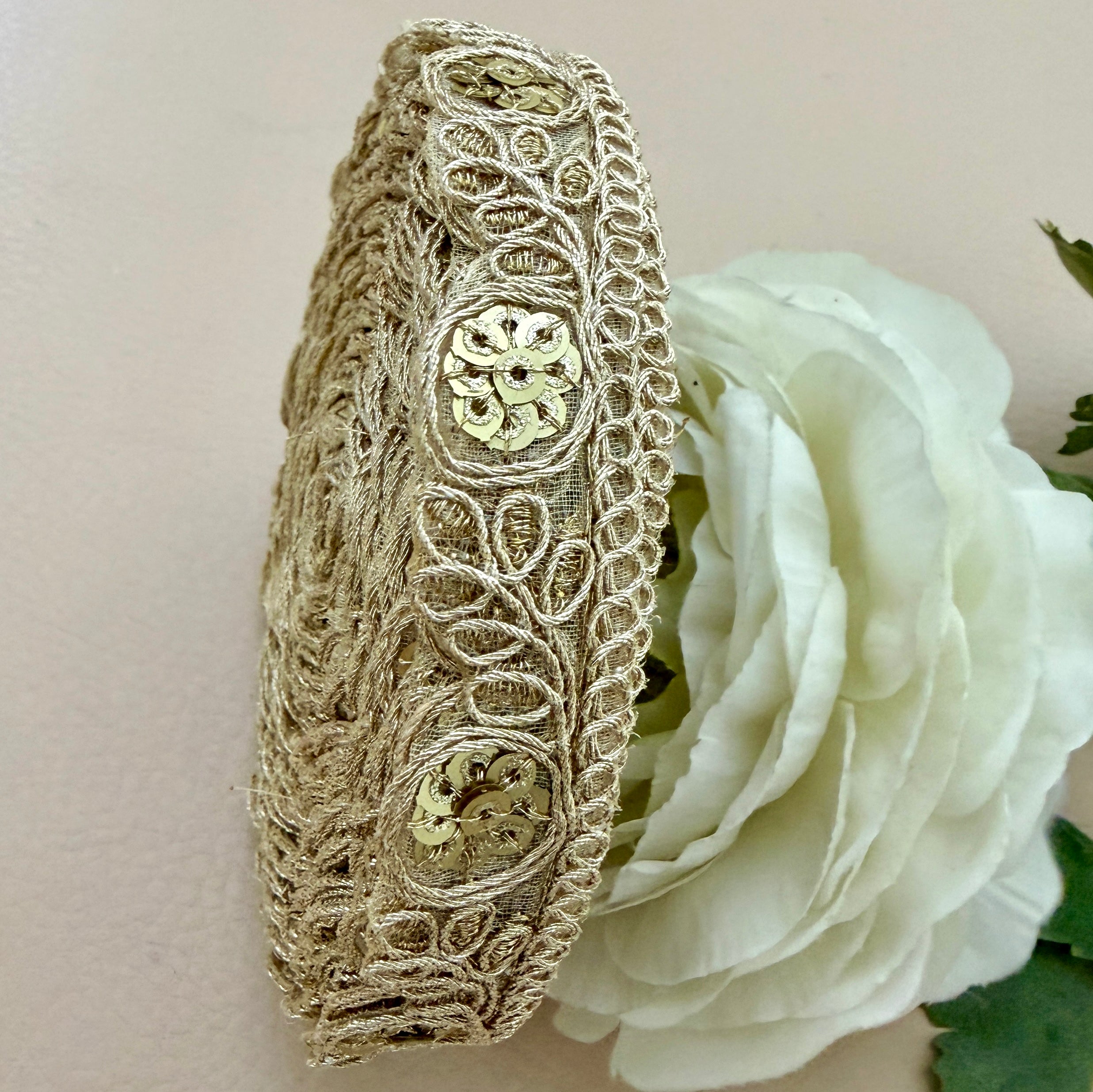 Decorative headband with intricate lace design on a white rose background