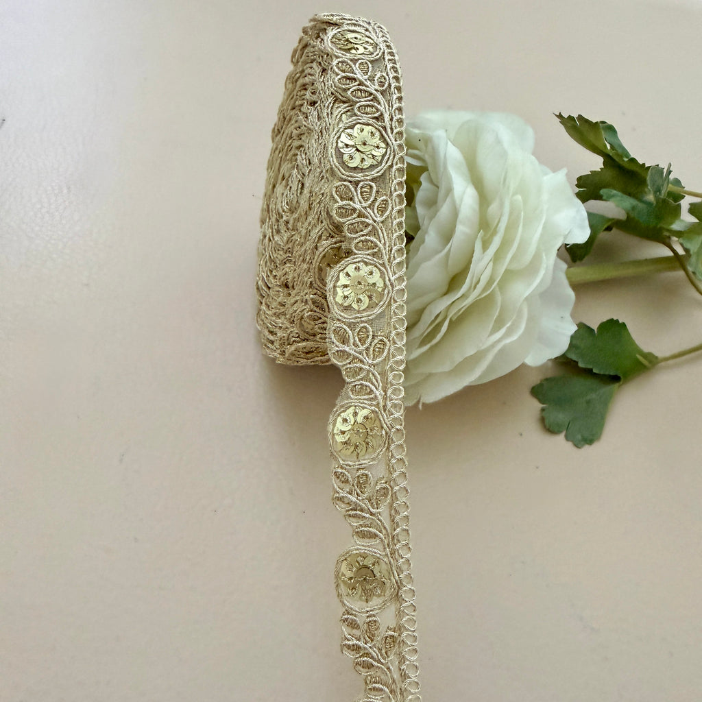 Decorative gold lace ribbon with a white rose on a beige background