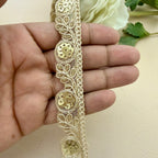 Gold lace trim held by a hand with a white flower in the background