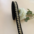 Black ribbon with gold decorative elements on a light background with a white rose.