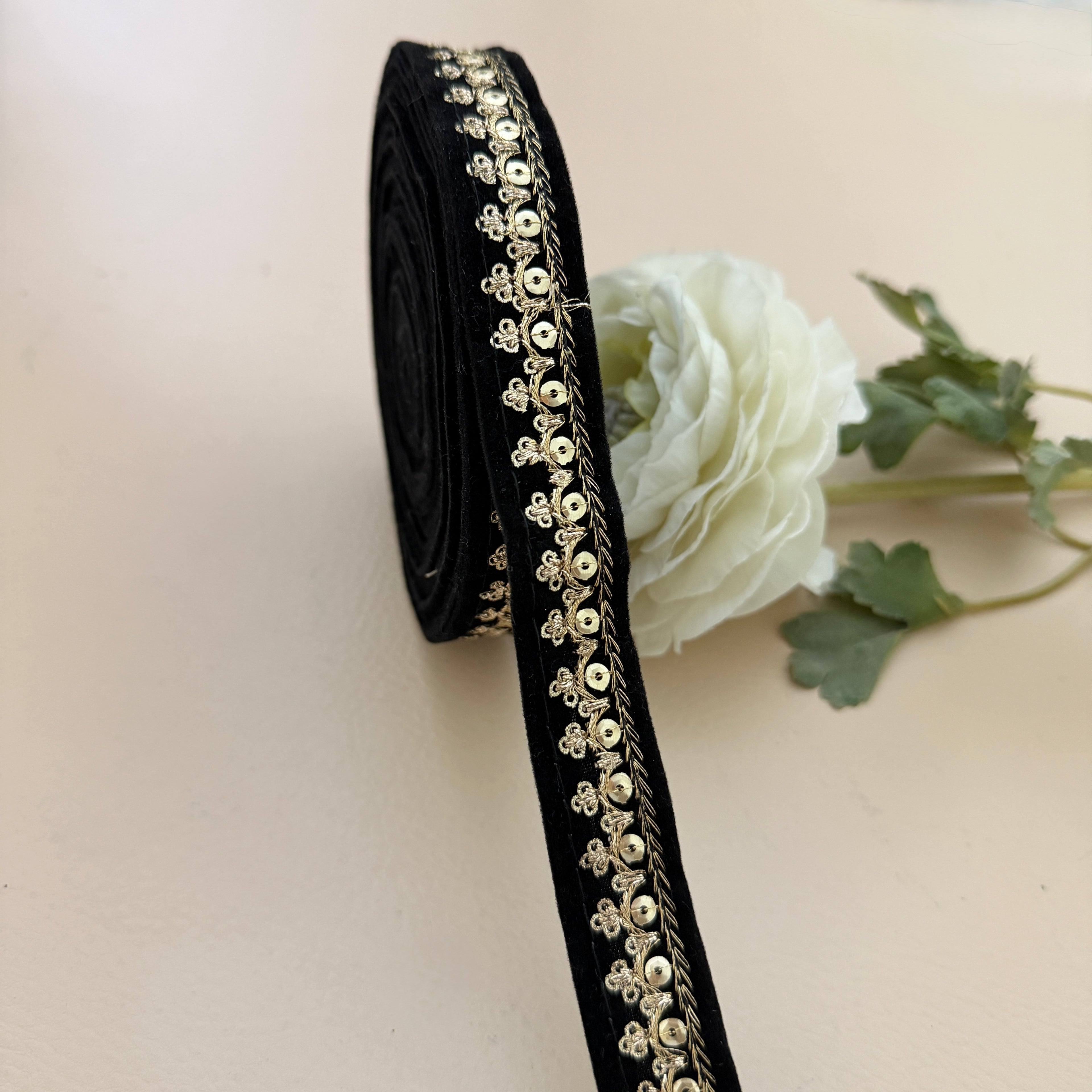 Black ribbon with gold decorative elements on a light background with a white rose.