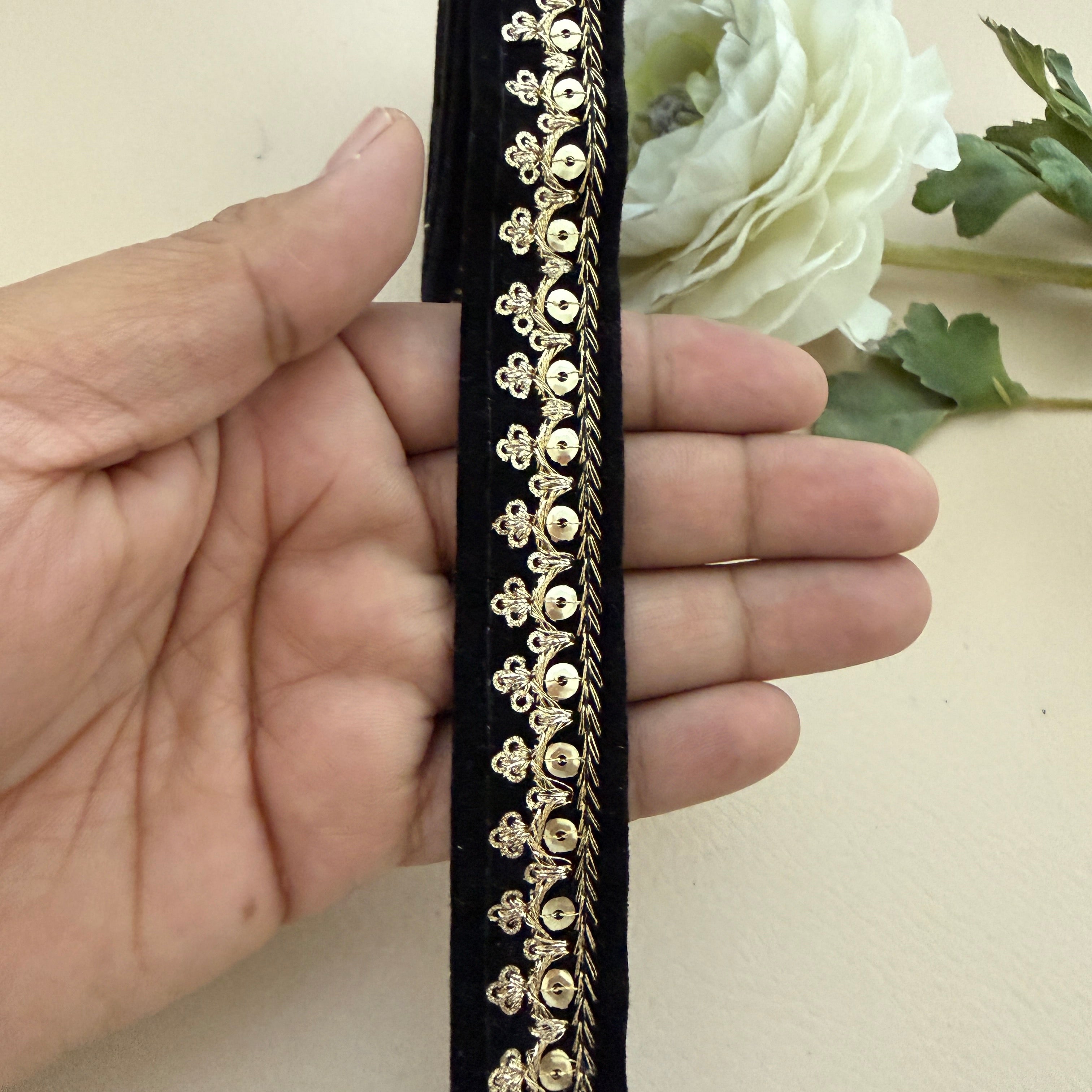 Decorative headband with gold embellishments held by a hand, with a white flower in the background.