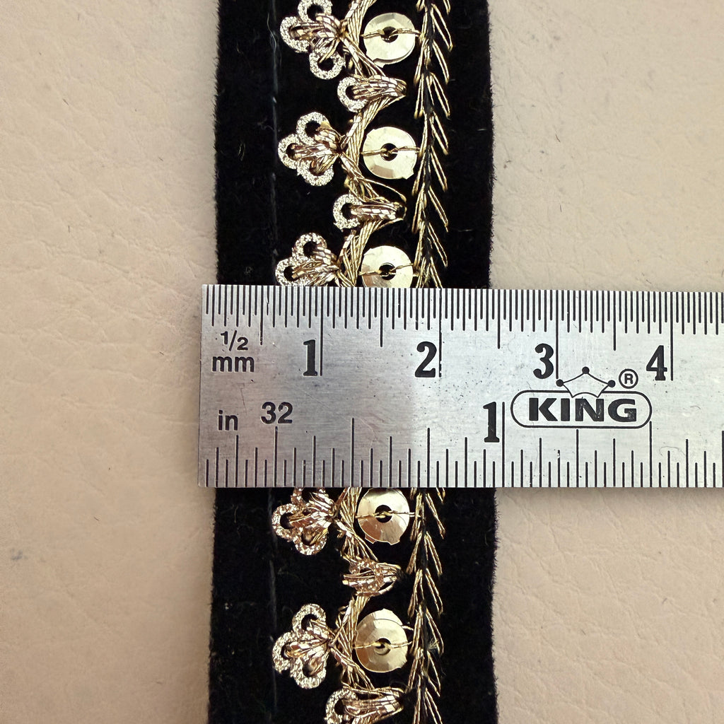 Gold floral embroidery on black fabric with a ruler for scale