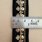Gold floral embroidery on black fabric with a ruler for scale