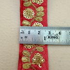 Red fabric with gold floral patterns and a ruler for measurement on a beige background