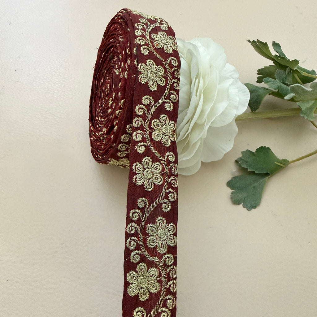Decorative ribbon with floral pattern next to a white flower on a beige background