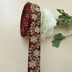 Decorative ribbon with floral pattern next to a white flower on a beige background