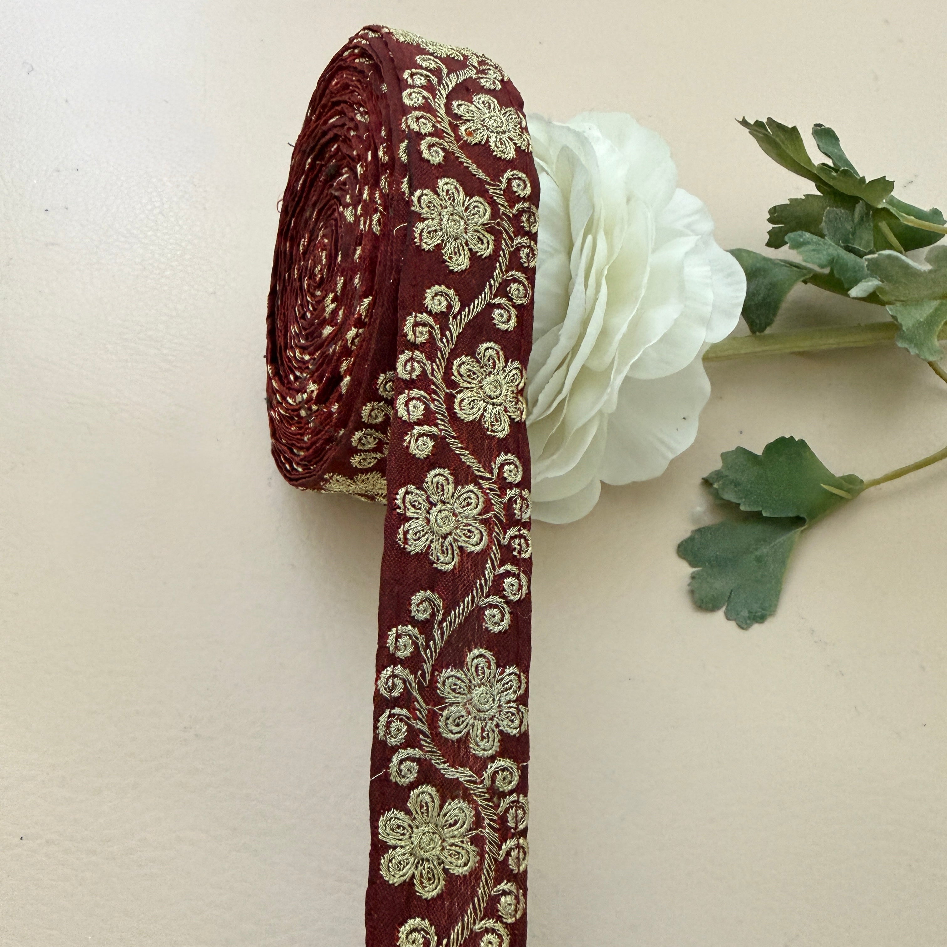 Decorative ribbon with floral pattern next to a white flower on a beige background
