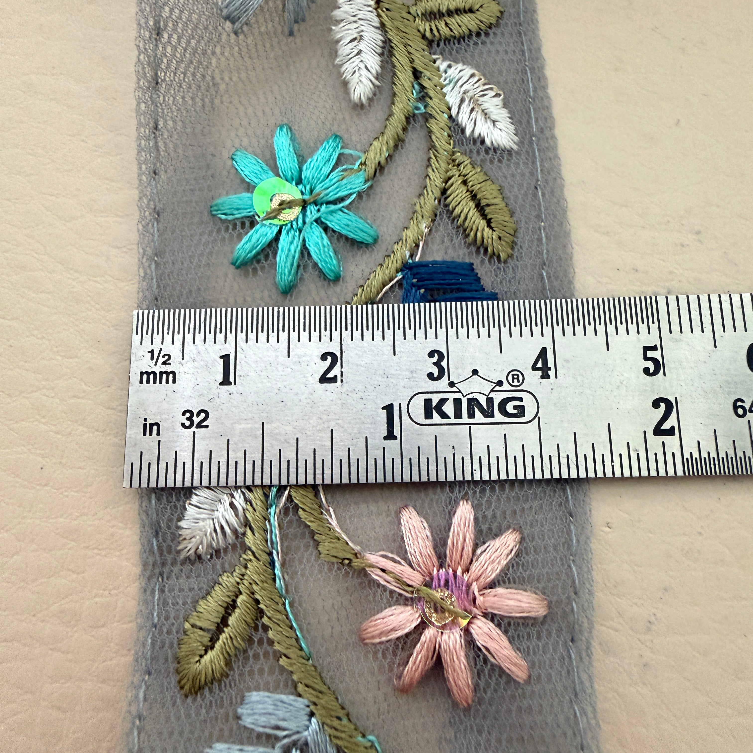 Embroidered flowers on fabric with a ruler for scale