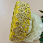 Decorative yellow ribbon with intricate gold patterns on a white flower background