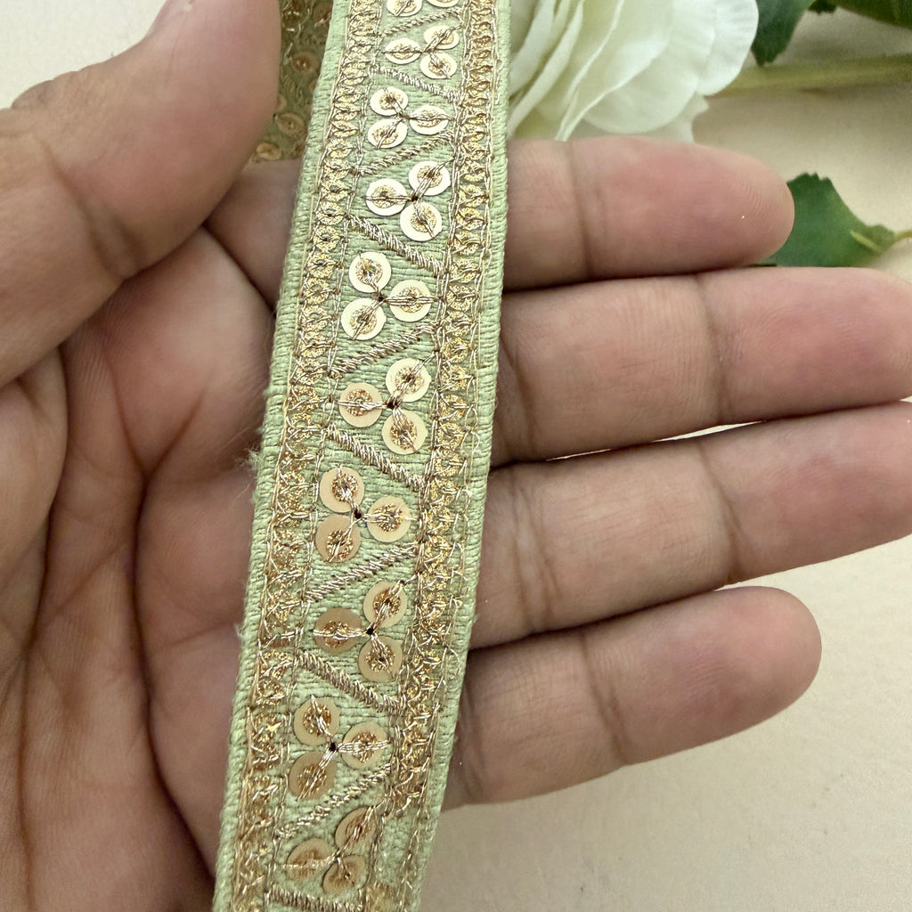 Decorative gold ribbon held between fingers with a blurred floral background
