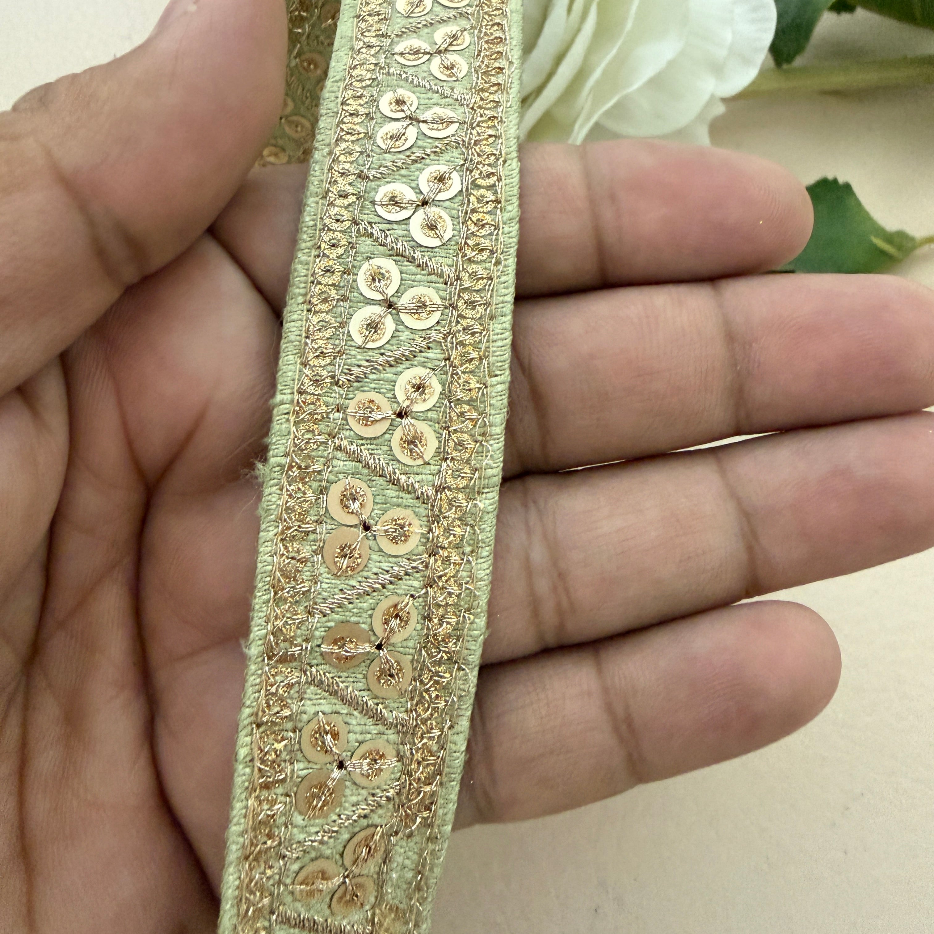 Decorative gold ribbon held between fingers with a blurred floral background