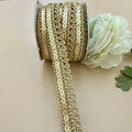 Gold sequin ribbon spool with a white flower on a beige background