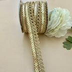 Gold sequin ribbon spool with a white flower on a beige background