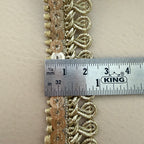 Decorative gold lace strip with a ruler for scale on a beige background