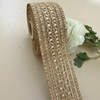 Roll of decorative gold ribbon with a white flower on a beige background