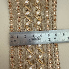 Decorative fabric trim with gold embroidery and a ruler for scale on a neutral background