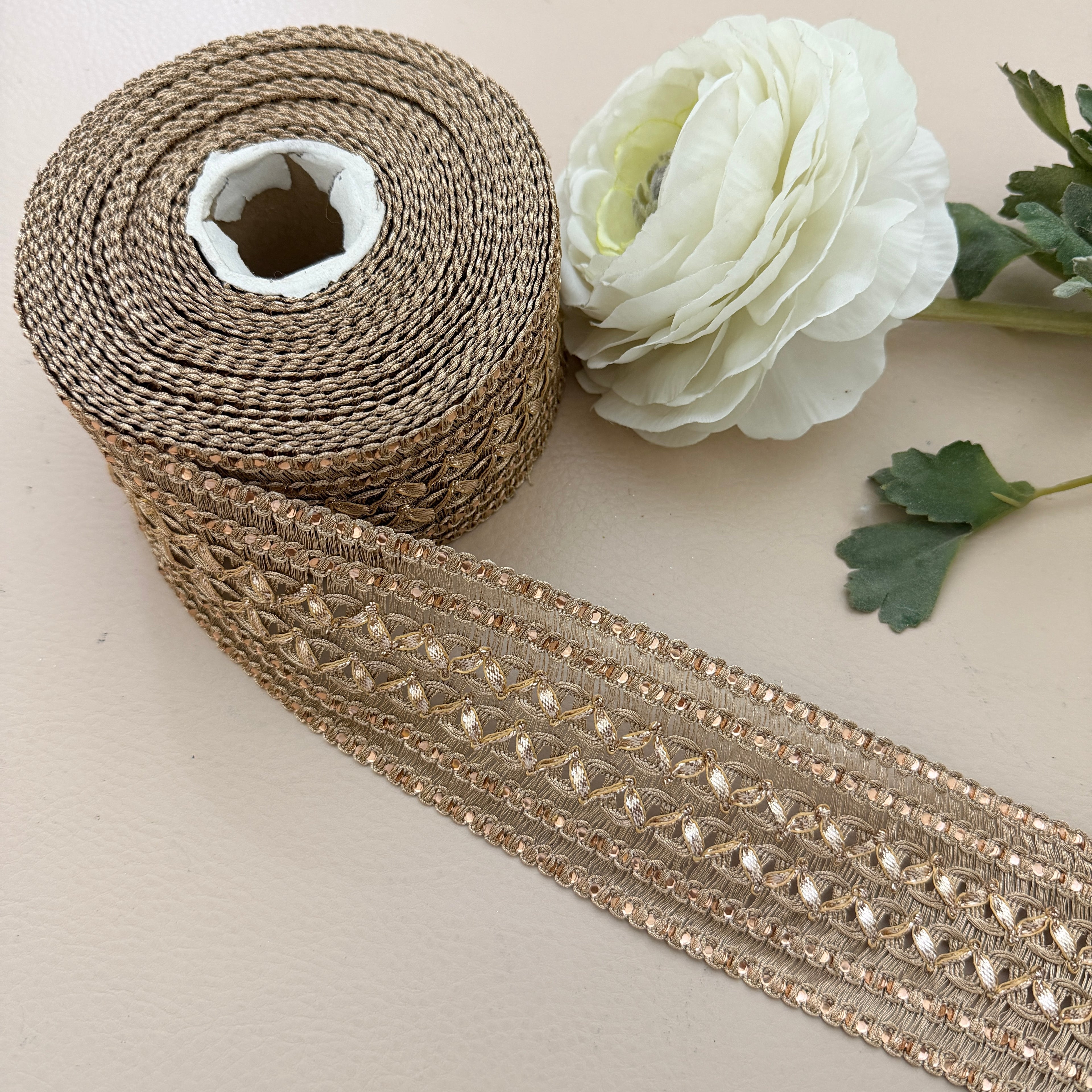 Roll of decorative ribbon with a white flower on a light background