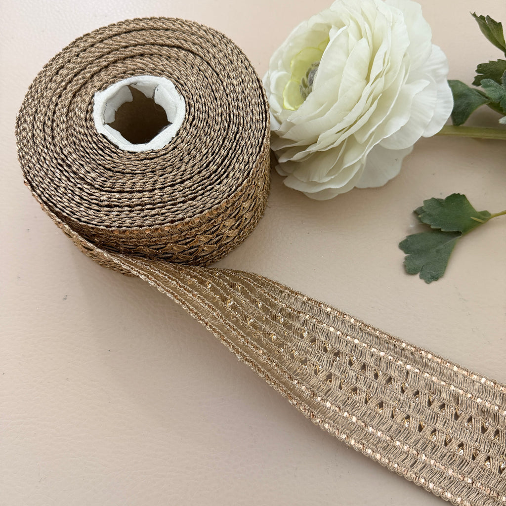 Roll of decorative ribbon with a white flower on a beige background