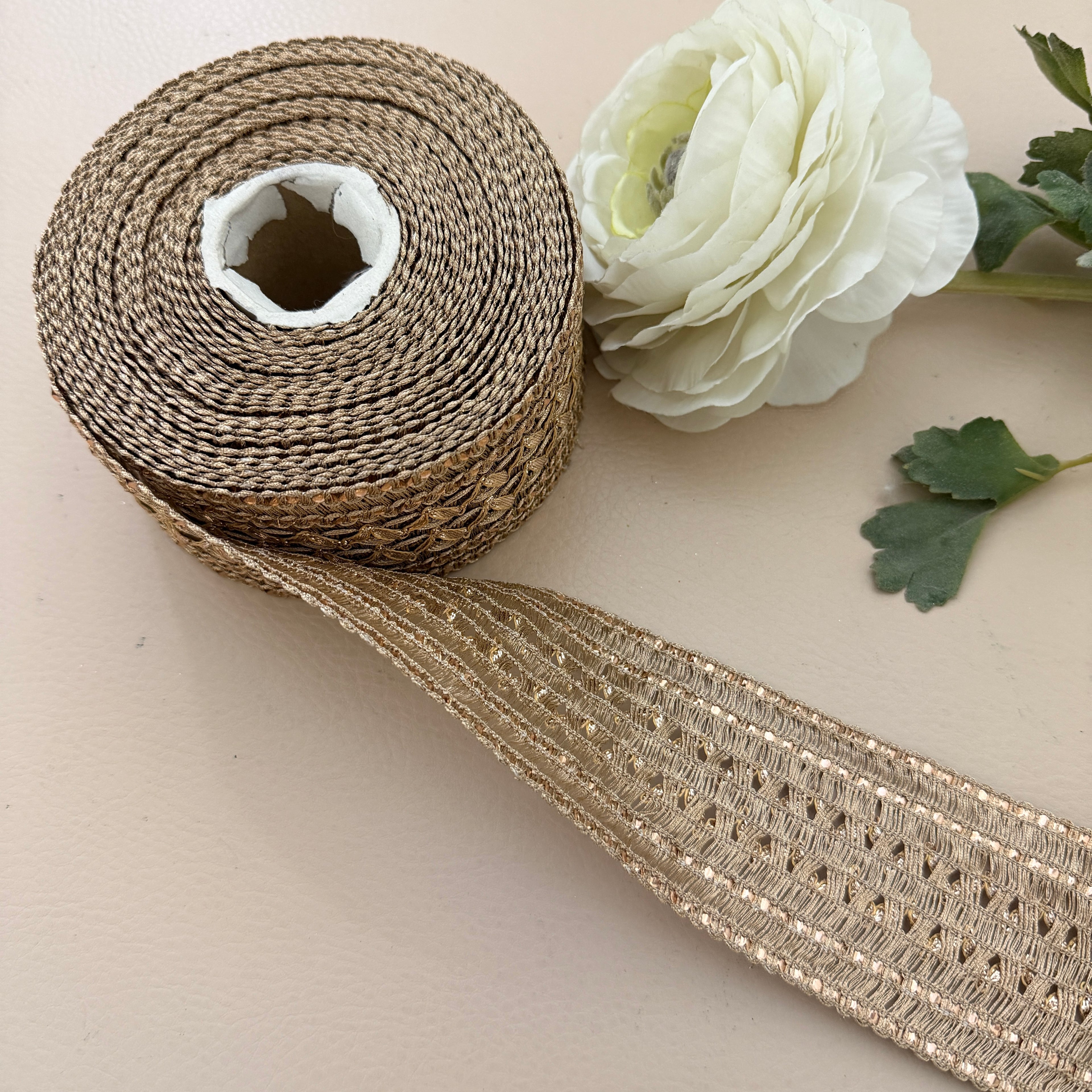 Roll of decorative ribbon with a white flower on a beige background