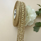 Decorative gold ribbon with beads and a white flower on a beige background