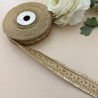 Roll of gold ribbon with a white flower on a beige background