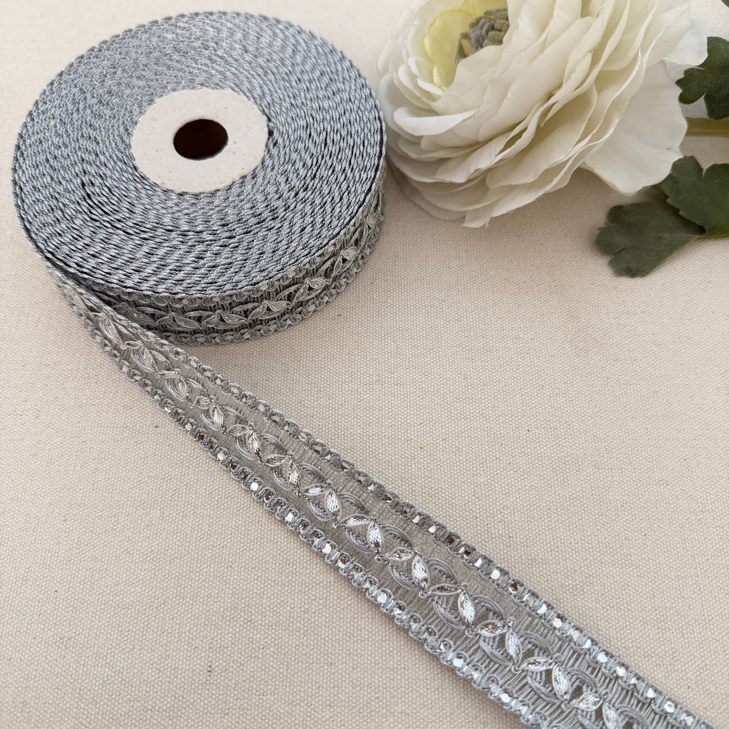 Decorative ribbon with crystals on a beige surface with a white flower.