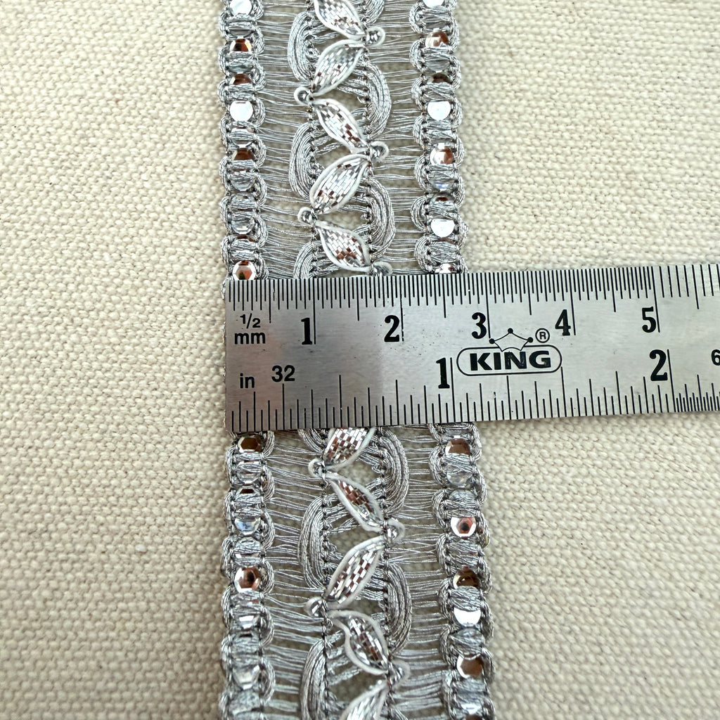 Decorative lace trim with a ruler for scale on a beige fabric background