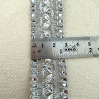 Decorative lace trim with a ruler for scale on a beige fabric background