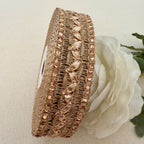 Decorative headband with rose gold accents on a neutral background with a white flower.