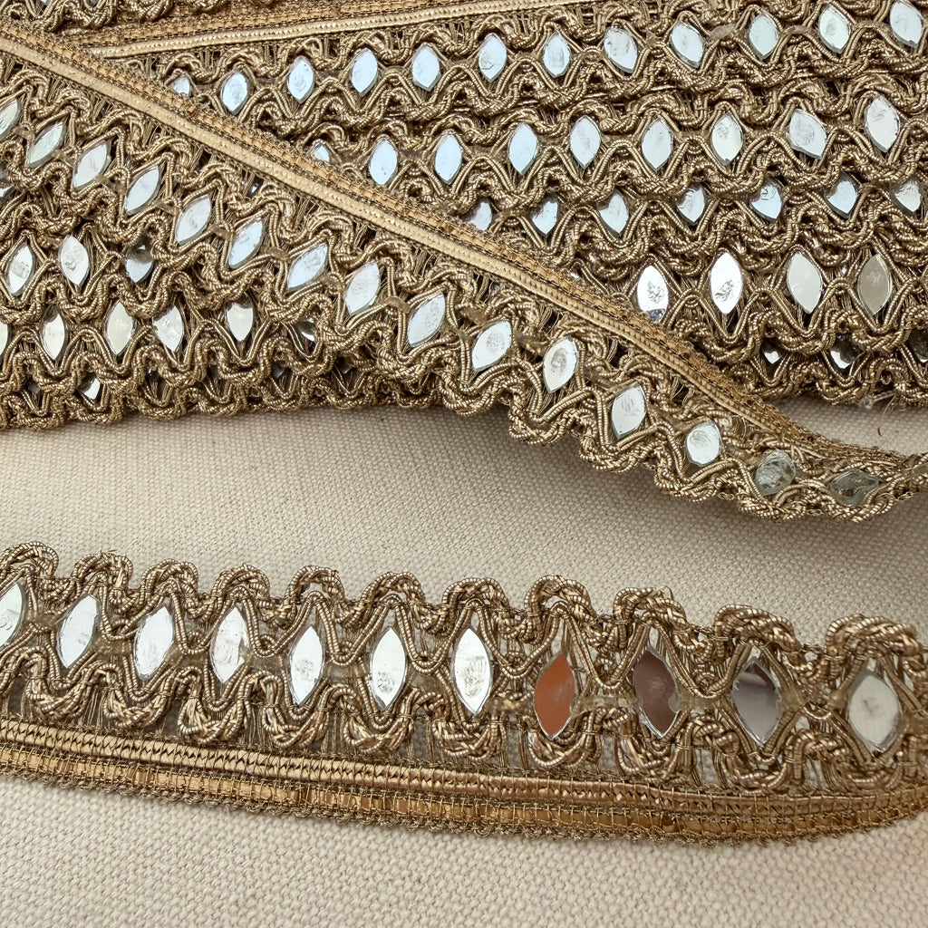 Decorative lace trim with reflective stones on a beige fabric background