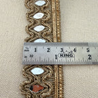 Decorative gold trim with reflective stones on a beige fabric background, measured by a King ruler.