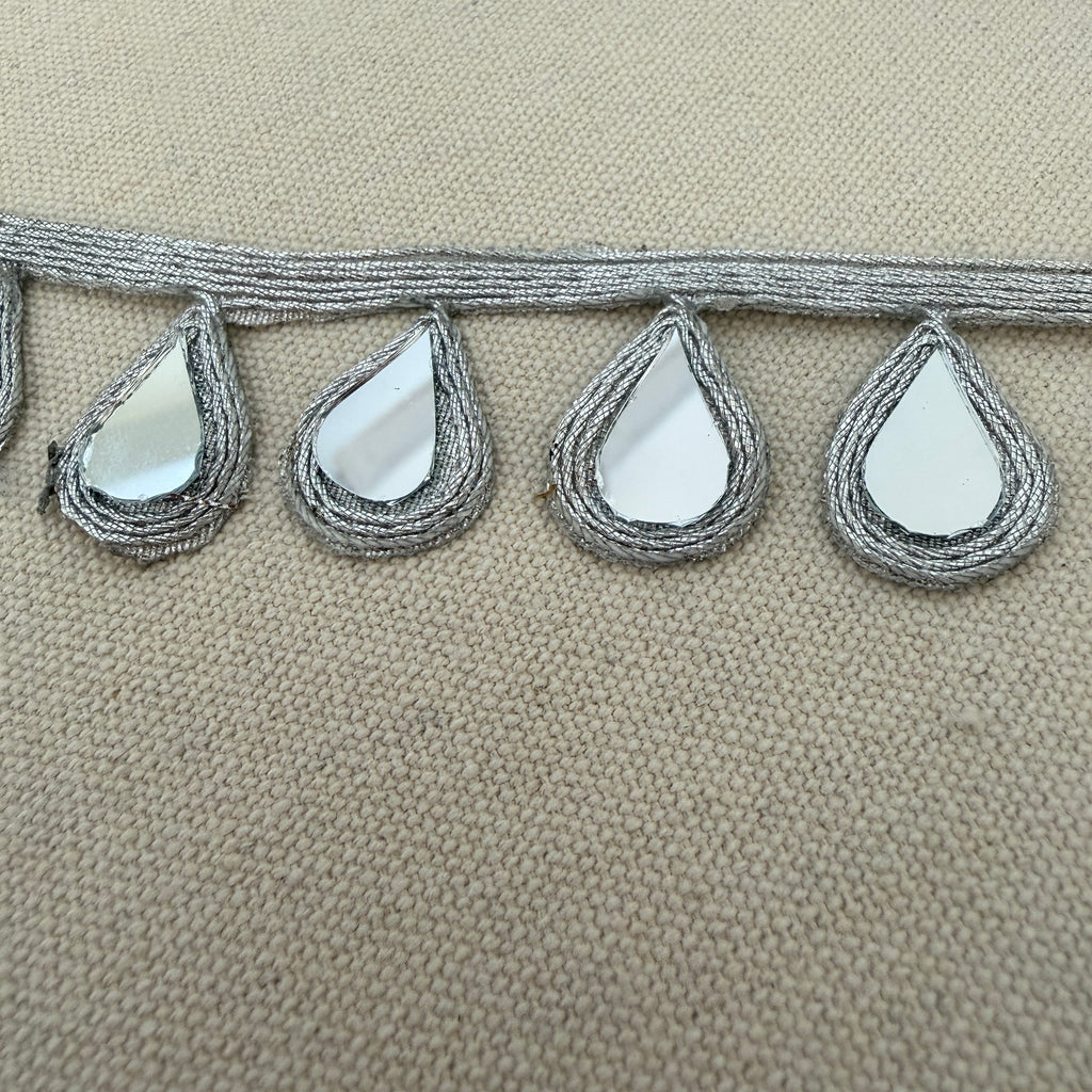 Decorative trim with teardrop-shaped mirrors on a beige background