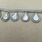 Decorative trim with teardrop-shaped mirrors on a beige background