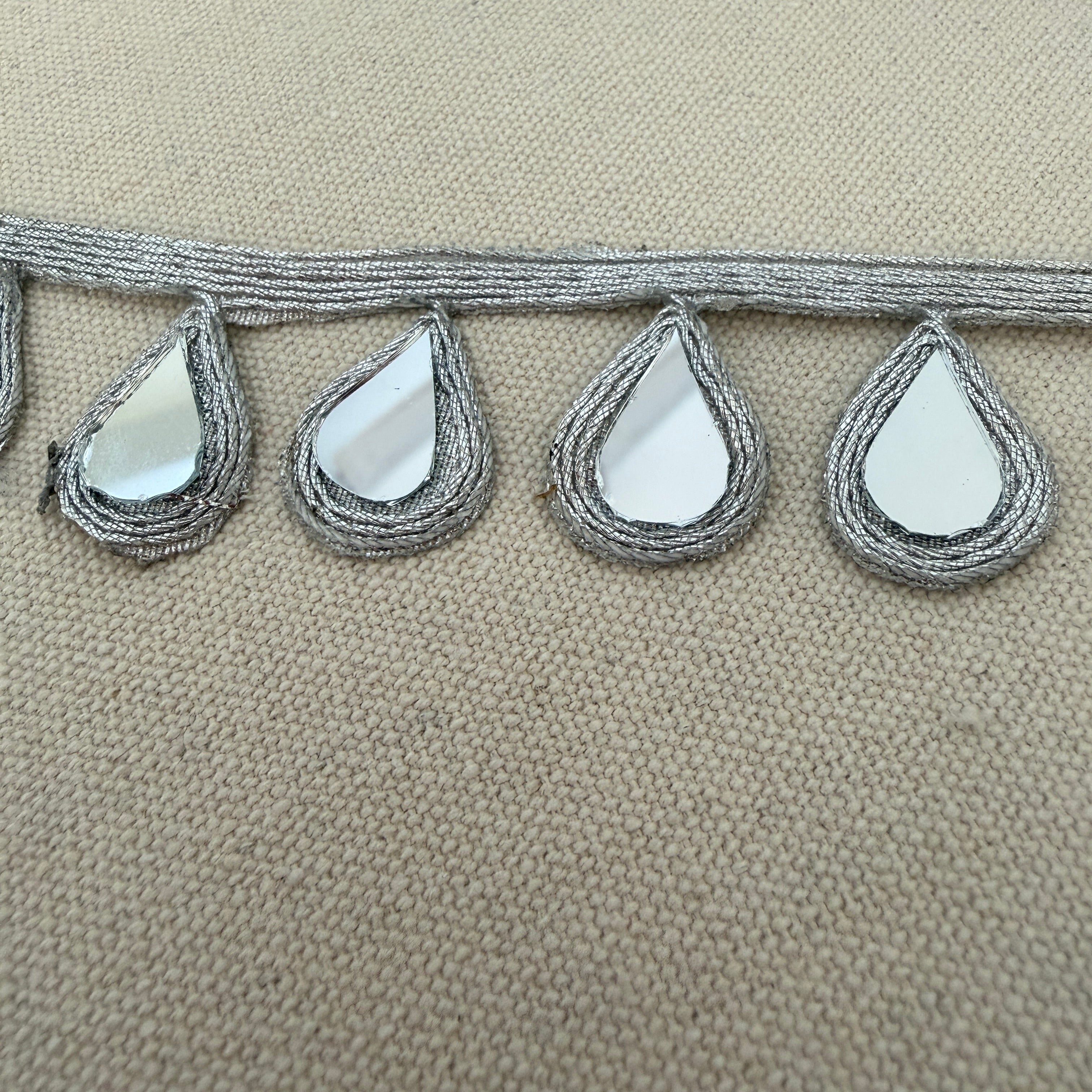 Decorative trim with teardrop-shaped mirrors on a beige background